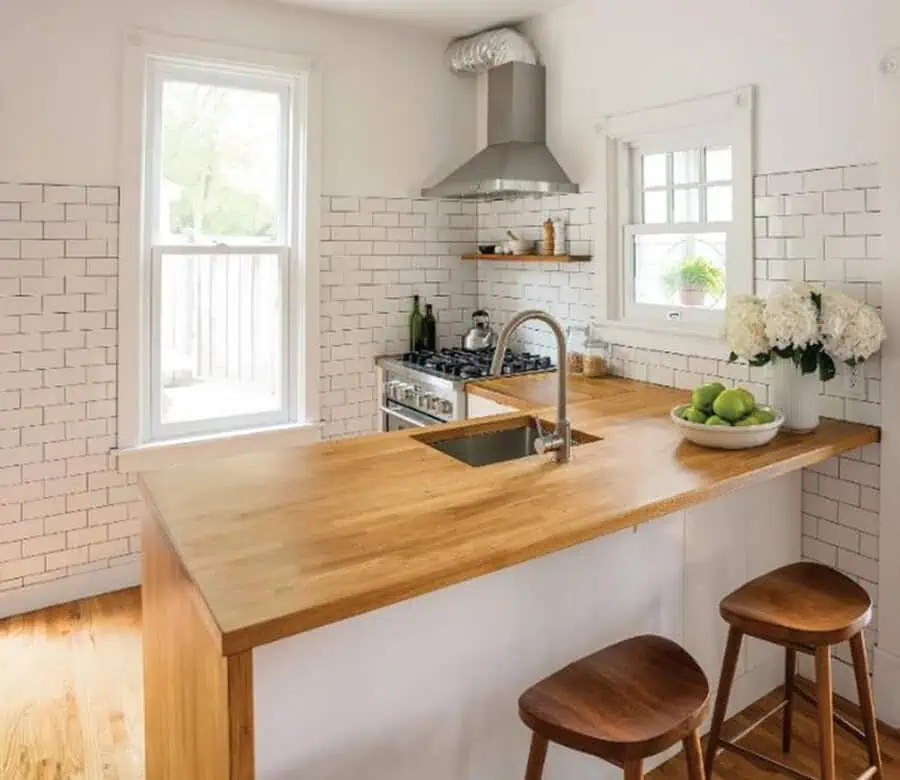 Kitchen with a single-hung window, white subway tile walls, and butcher block countertop.