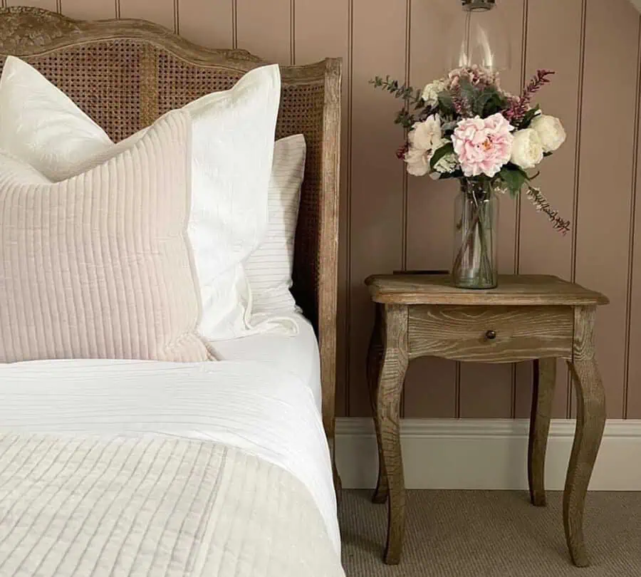 Blush and cream floral arrangement in a glass vase on a rustic nightstand, adding softness to a warm-toned bedroom.