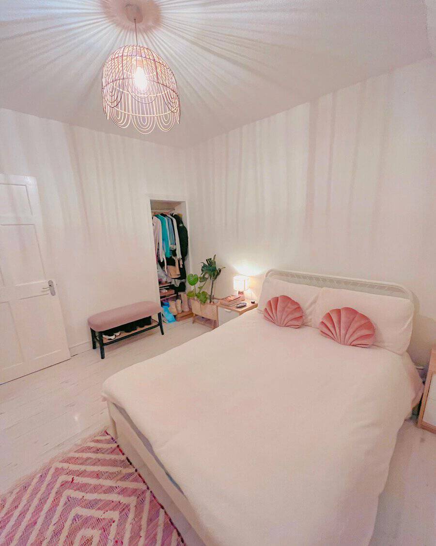Textured pink rug adds warmth and style to a cozy bedroom with soft neutral tones.