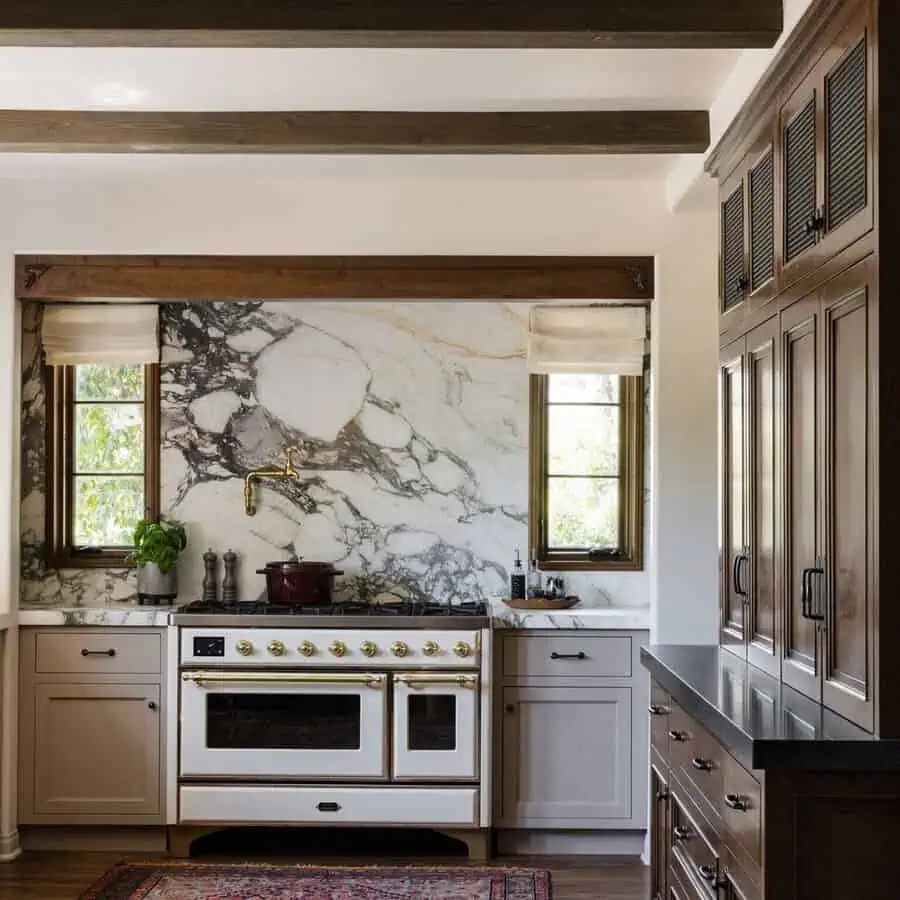 Spanish-style kitchen with wood beams, a marble backsplash, dark wood cabinetry, and a vintage-style range with brass accents.