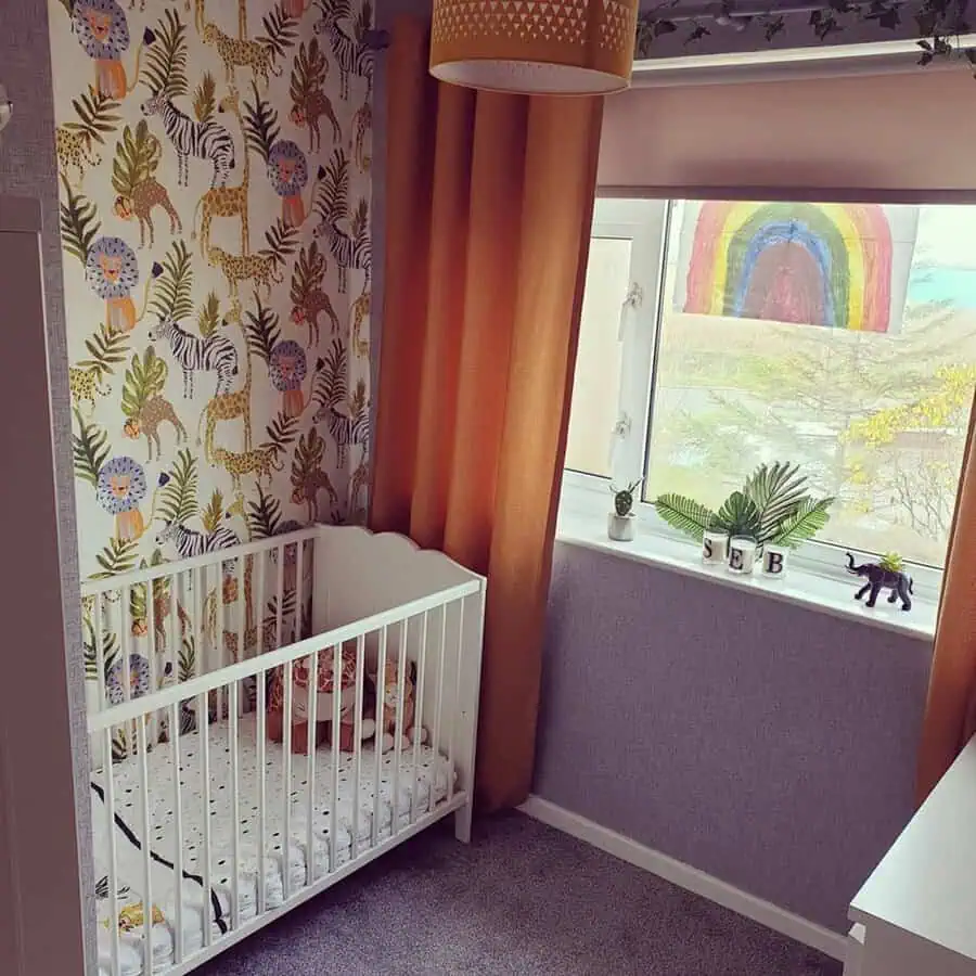 Nursery with safari wallpaper, orange curtains, white crib, and a colorful rainbow for a playful, sunny look.