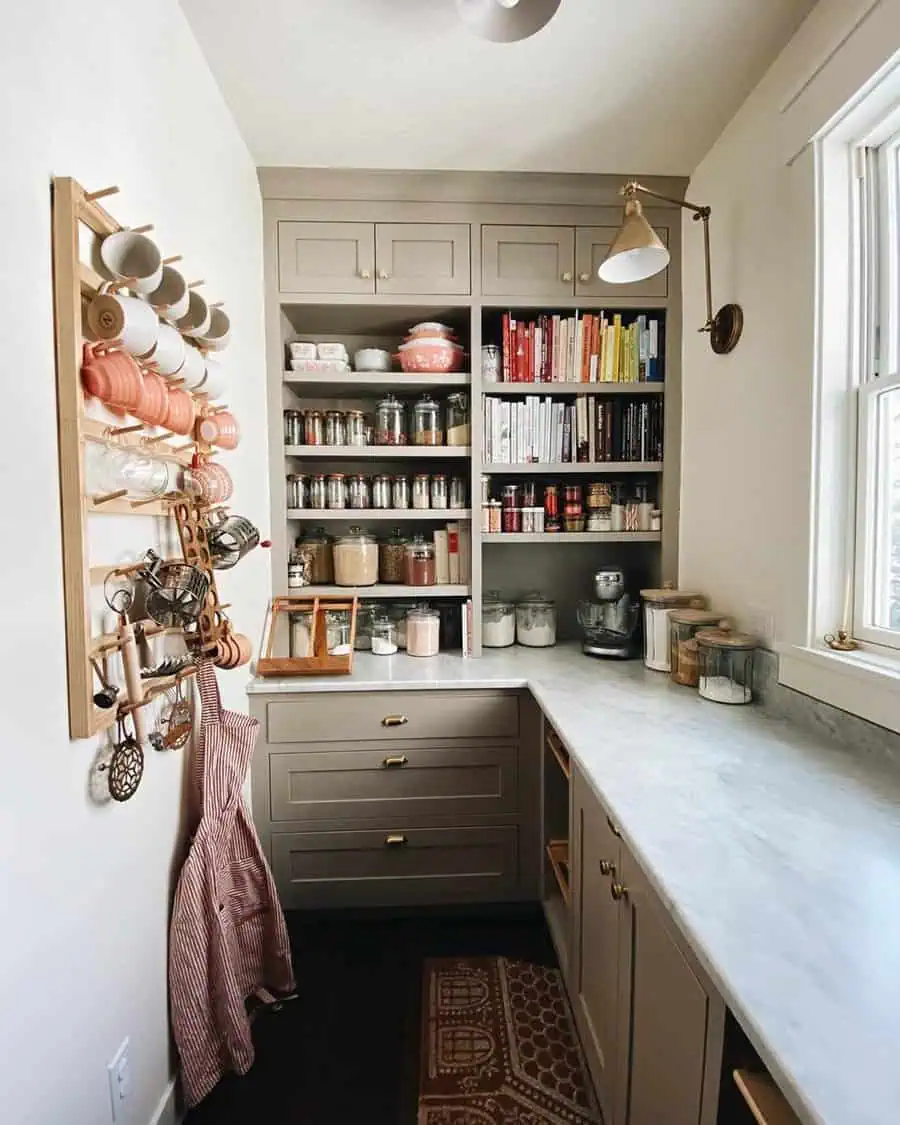 Pantry with neutral cabinets, marble counters, and a peg rack of mugs for a warm, organized cooking space.