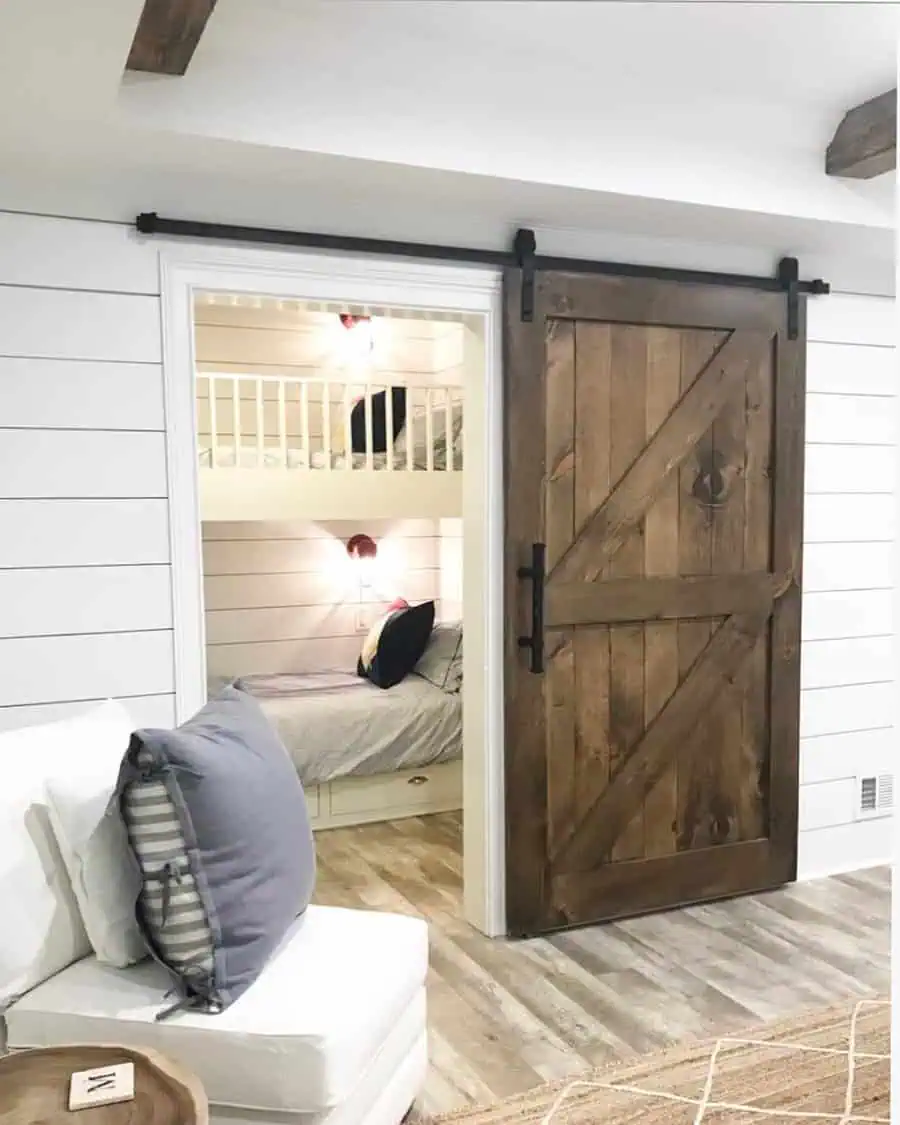 Sliding barn door with built-in bunk beds and shiplap walls for a cozy, farmhouse-style spare room.