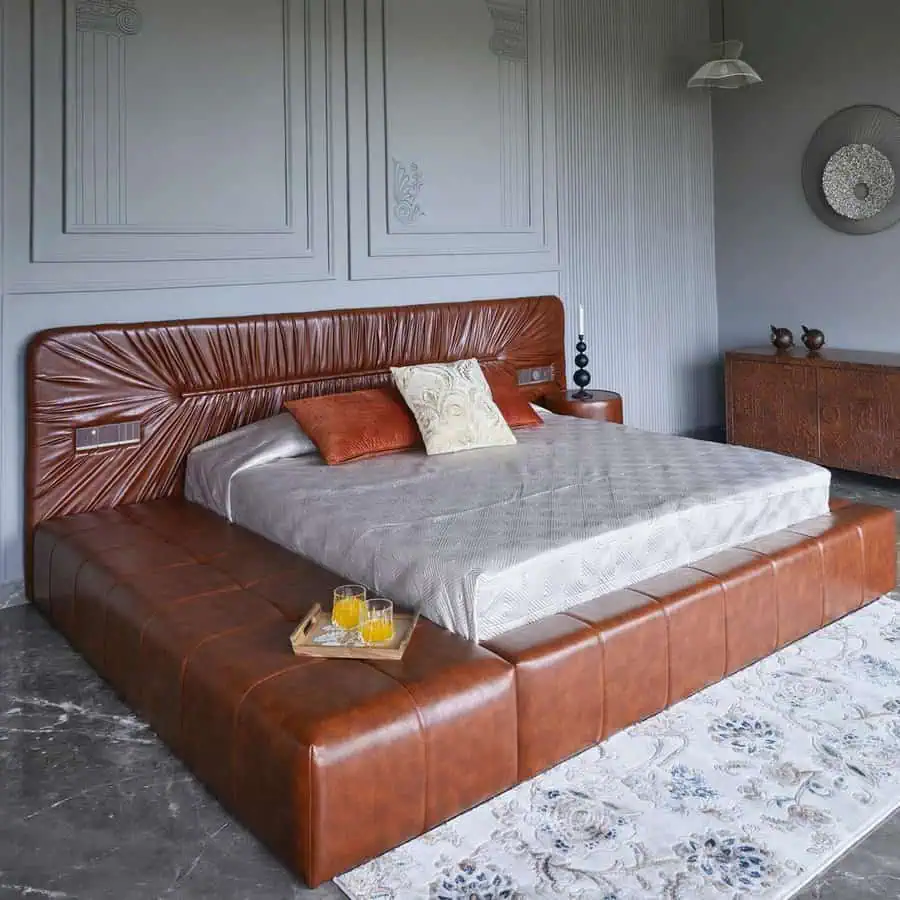 Leather platform bed with extended sides serving as seating and nightstands, blending function and style in a sophisticated design.