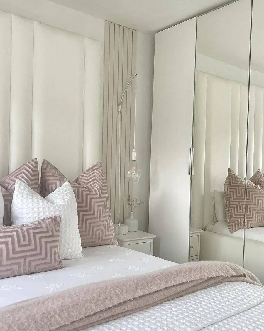 Soft pink and white patterned pillows add texture and contrast to a chic, neutral-toned bedroom.