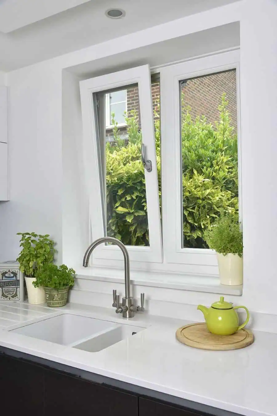White tilt & turn kitchen window above a minimalist countertop with fresh herbs.