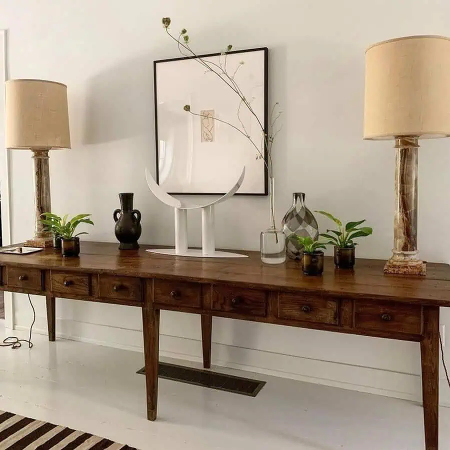 Living area with white painted wood floor, a rustic console, neutral lamps, and minimal art.