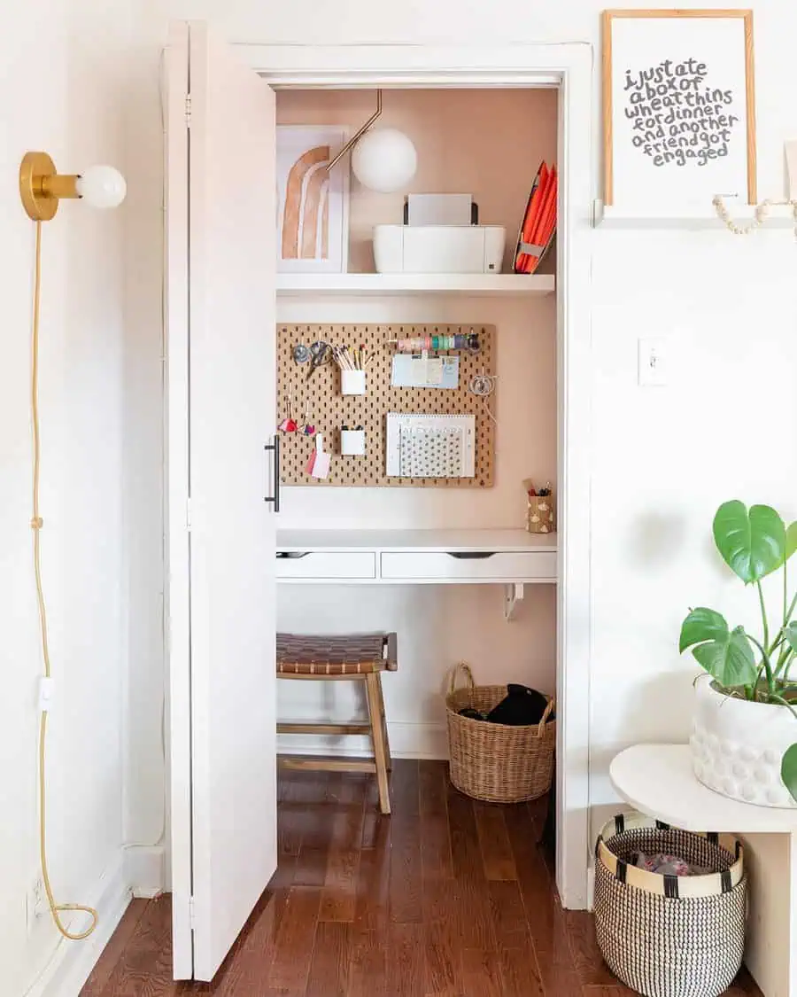 Closet office with a pegboard organizer, white desk, floating shelves, woven stool, soft neutral tones, and warm storage baskets.