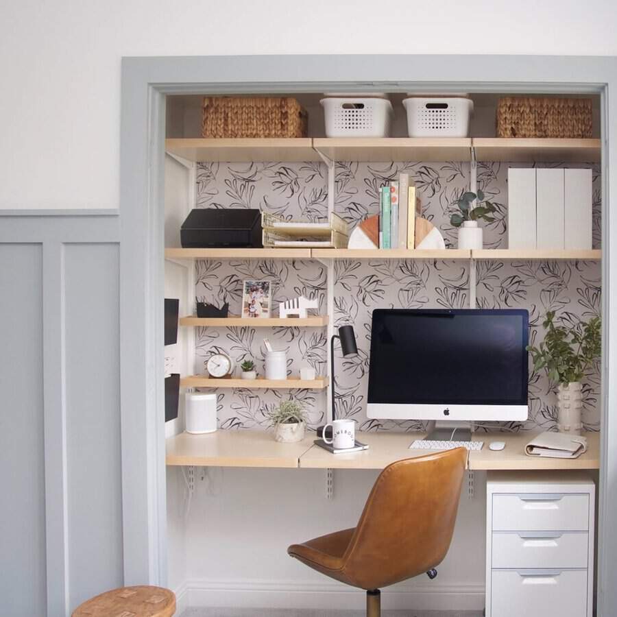 Closet turned into a home office with floral wallpaper, floating desk, and organized shelves for a compact, stylish workspace.