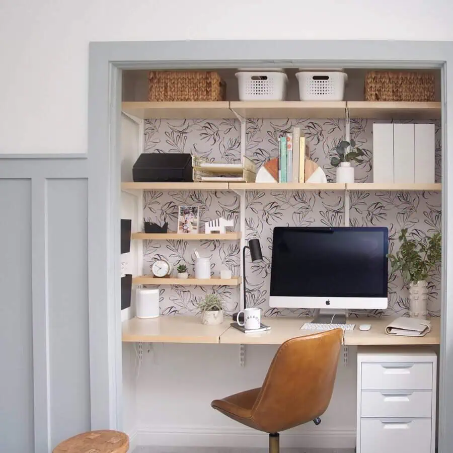 Closet turned into a home office with floral wallpaper, floating desk, and organized shelves for a compact, stylish workspace.