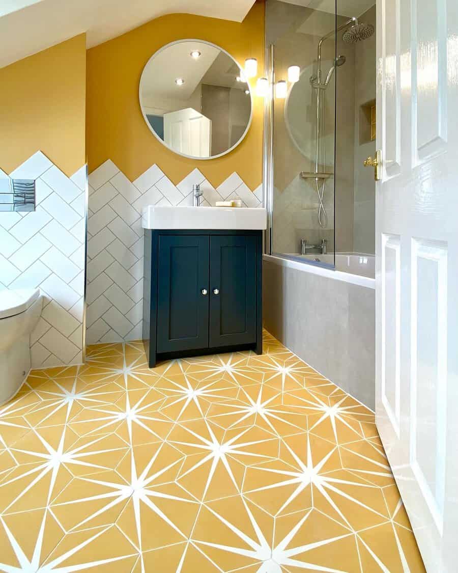 Contemporary bathroom with geometric yellow floor tiles, mustard walls, black vanity, and a glass shower.